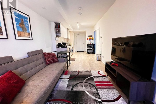 Living room with sofa, tv, artwork, and view of the kitchen. - 2520 - 19 Western Battery Road, Toronto
