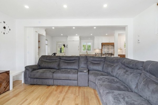 Open-concept living area showing a grey sectional sofa, hardwood floors, and view to the kitchen. - 2523 Rue St-louis, Gatineau