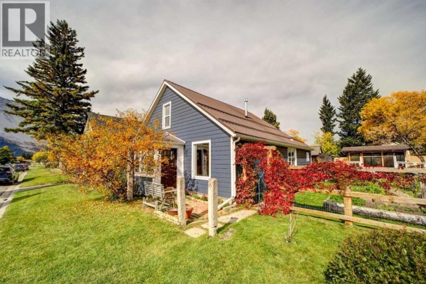 Blue house with fall foliage, wooden fence, and trees in the front yard. - 2526 211 Street, Bellevue