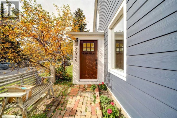 Front door of the blue house with a brick walkway and a wooden bench. - 2526 211 Street, Bellevue