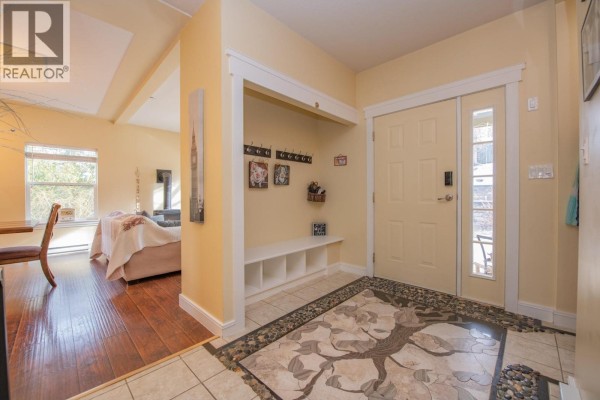 Foyer with a view into the living area, featuring a decorative rug and natural light. - 2529 Cedar Ridge Court, Lumby