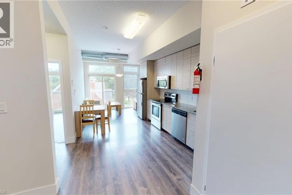Open-concept kitchen with wooden cabinetry, stainless steel appliances, and dining area. - 253 Albert Street Unit# 216, Waterloo
