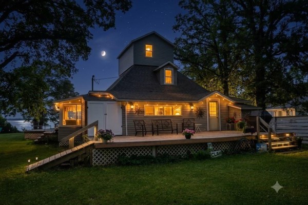 House at night with lights on decks and windows, crescent moon visible. - 253 Gimli Road, Whytewold
