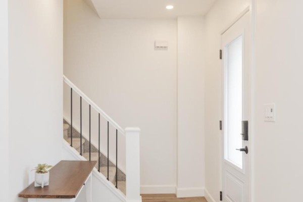 Interior view of a bright white entryway with stairs to the left and a glass-paneled door to the right. - 253 Second Avenue W, North Bay