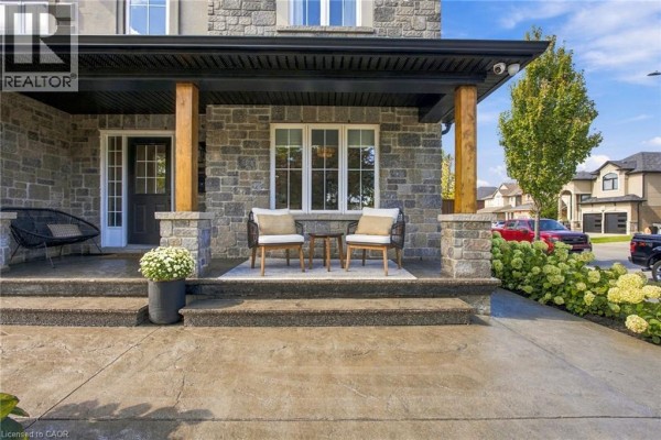 Close-up of the front porch with seating, stone pillars, and a dark front door. - 253 Upper Mount Albion Road, Stoney Creek