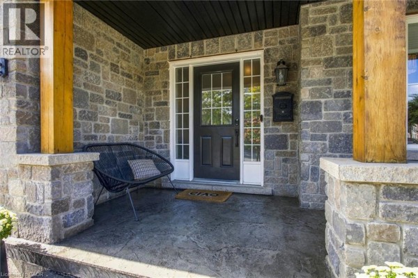 Close-up of the dark front door with sidelights on a stone porch with a chair. - 253 Upper Mount Albion Road, Stoney Creek