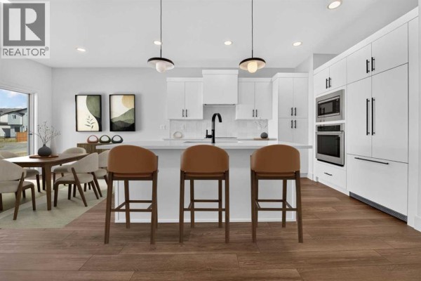 Open concept kitchen and dining area with white cabinets, a kitchen island, and dining table with chairs. - 2530 44 Street S, Lethbridge