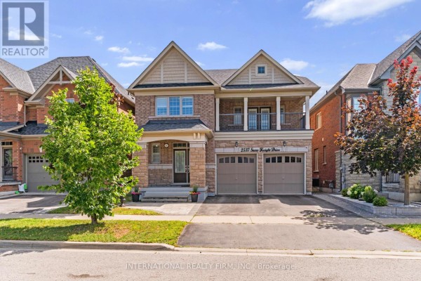 Exterior of a two-story brick and stone house on a sunny day with a green tree. - 2537 Snow Knight Drive, Oshawa
