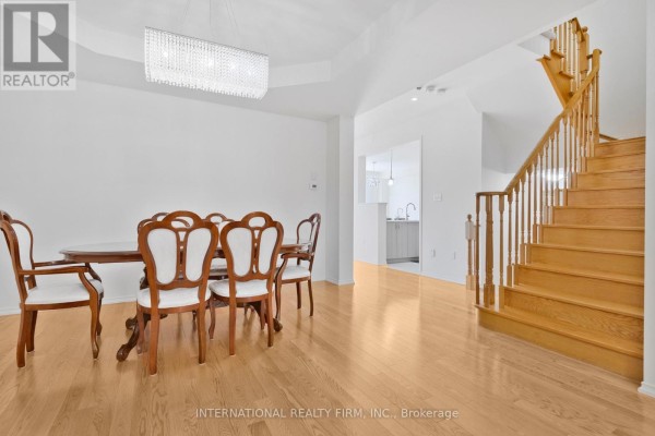 Dining area with a wooden table and chairs, and a wooden staircase leading upstairs. - 2537 Snow Knight Drive, Oshawa
