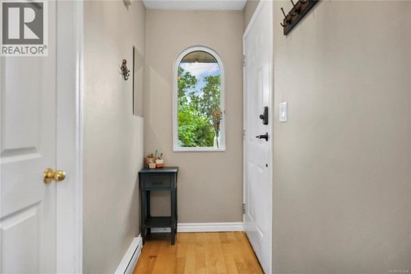 Interior hallway with a white door, arched window, and a small dark table. - 2539 Cedar Hill Rd, Victoria