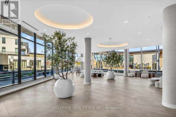 Spacious, modern lobby with large windows, modern furniture, and decorative trees in large white planters. - 254 - 333 Sunseeker Avenue, Innisfil