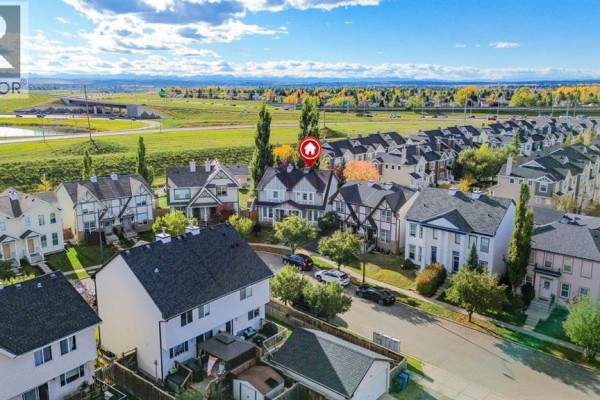 Daytime aerial view of a residential neighborhood with duplexes and a distant mountain range. - 254 Elgin View Se, Calgary
