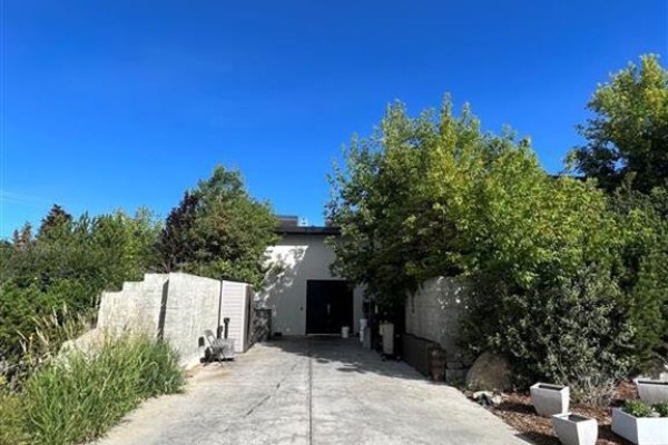 Driveway leading to the rear of the building with greenery - 254028 Bearspaw Road, Rural Rocky View County
