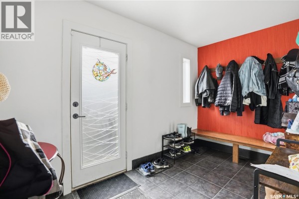 Interior entryway with a door, orange textured wall, and shoe rack. - 2543 Garnet Street, Regina