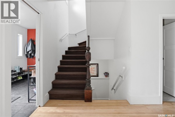 Interior view of a staircase with dark brown carpet and wooden banister. - 2543 Garnet Street, Regina