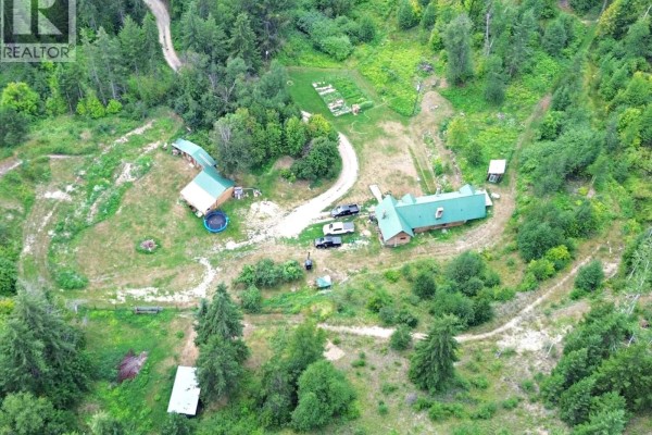 Outdoor wood shed with stacked firewood and surrounding trees in a rural setting. - 2545 Child Road, Clearwater