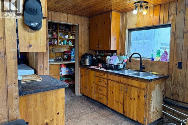 Attic room with a mattress, storage boxes, and a small window with wood-paneled walls. - 2545 Child Road, Clearwater