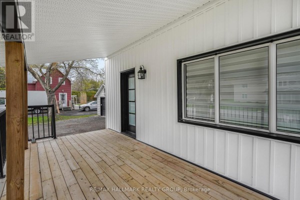 Backyard with green lawn, wooden deck, and view of adjacent structures. - 2545 Market Street, Ottawa
