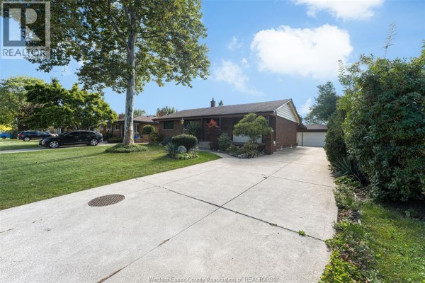 Wide concrete driveway leading to a brick bungalow with a two-car garage on the right. - 2545 St. Patricks's Avenue, Windsor
