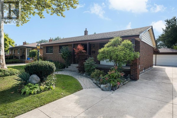 Exterior view of a residential brick home with a paved driveway and lush green landscaping. - 2545 St. Patricks's Avenue, Windsor