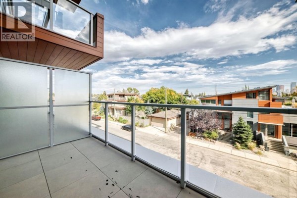 Balcony view overlooking a residential street with houses and distant city skyline. - 255, 110 18a Street Nw, Calgary