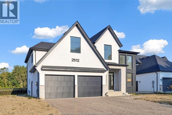 Front view of a modern two-story house with a gray driveway and garage doors. - 255 Dolores, Essex