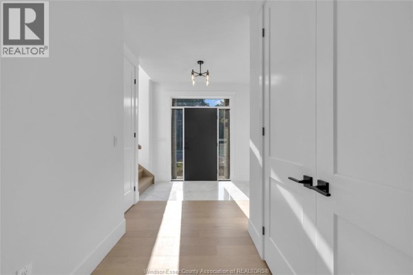 Bright interior hallway with white walls, wood floors, and a black front door. - 255 Dolores, Essex