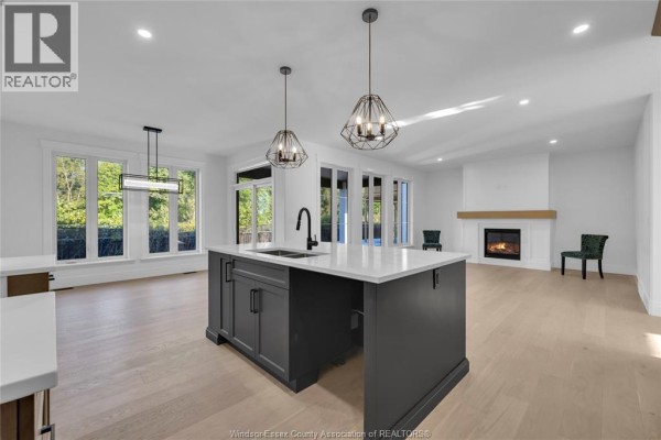 Open concept living area with a dark gray kitchen island, white countertops, and fireplace. - 255 Dolores, Essex