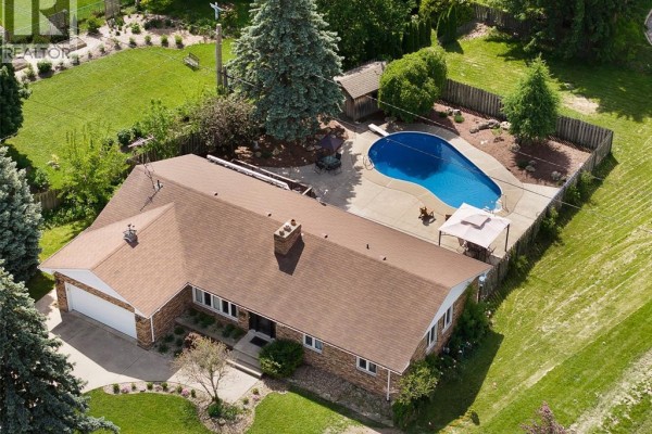 Backyard with concrete patio, inground pool, chairs, tables, and mature trees. - 255 Fort Street, Amherstburg