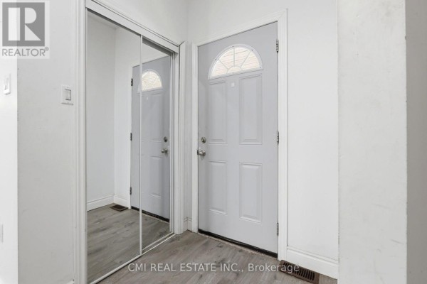 Interior entryway with a white door, mirrored closet, and light grey laminate flooring. - 255 Hall Avenue, Windsor