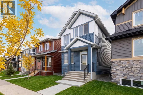Exterior of a blue and white house with attached dark grey and red houses on either side. - 255 Lucas Gate Nw, Calgary
