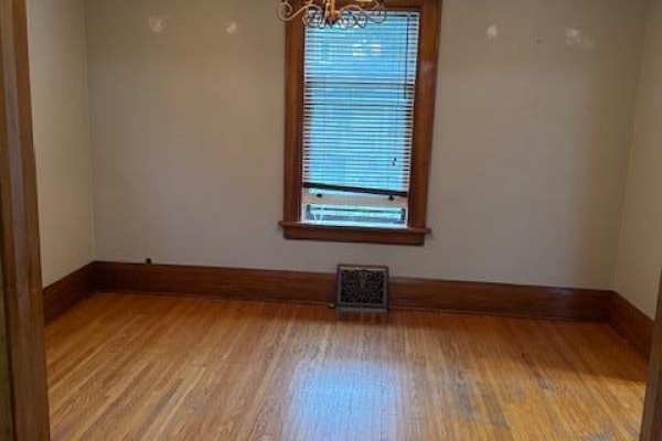 Empty room with hardwood floors, tan walls, and a single window. - 255 Main Street, Cambridge