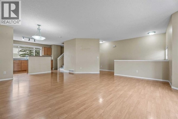 Open concept living and dining area with light wood floors and beige walls. - 255 Prestwick Acres Lane Se, Calgary