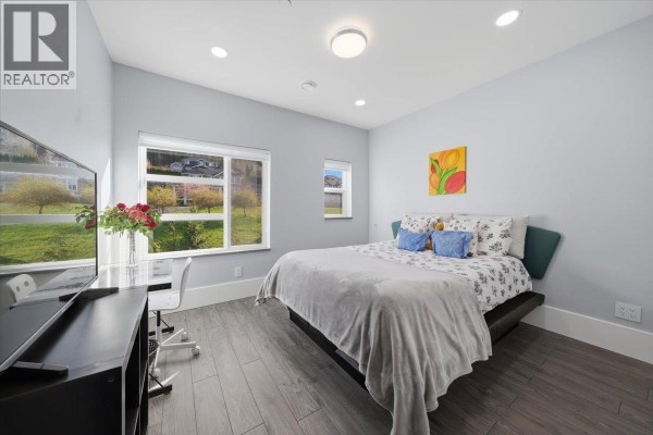 Covered front porch with modern grey siding, double glass doors, and outdoor seating area with a Canadian flag. - 25507 Bosonworth Avenue, Maple Ridge