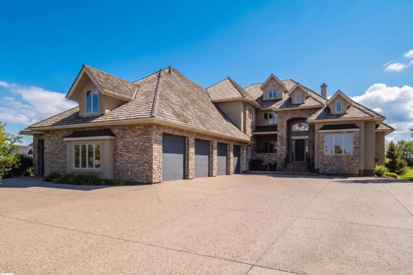 Front exterior of the residence with a stone facade and a four-car garage. - #11 25515 Twp Road 511a, Rural Parkland County