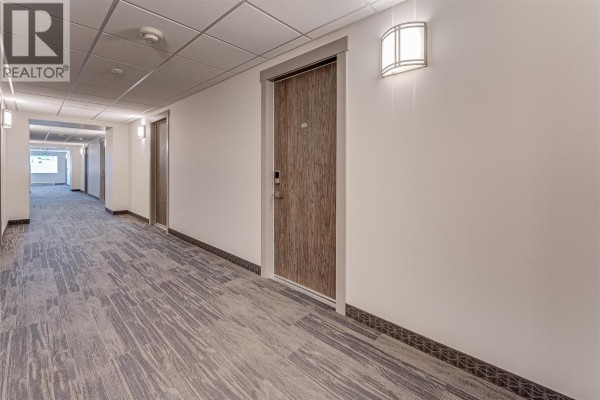 Hallway with carpeted flooring, light fixtures, and apartment doors - 2555 Lakeshore Road Unit# 321, Vernon