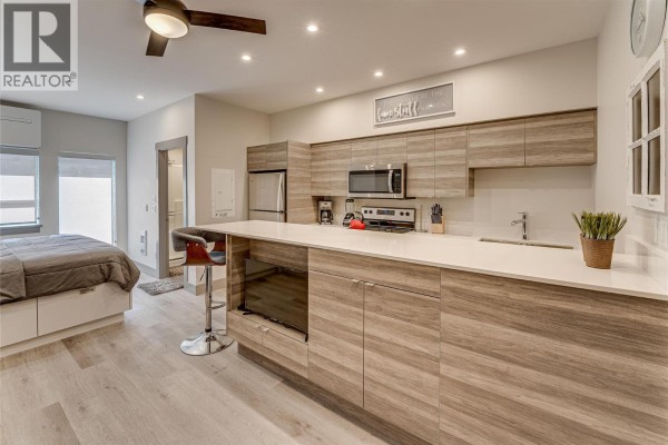 Open-concept kitchen featuring wood cabinetry, stainless steel appliances, and a breakfast bar - 2555 Lakeshore Road Unit# 321, Vernon