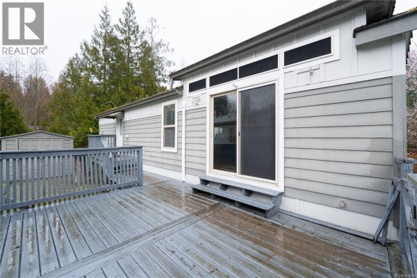 Back view of mobile home with sliding door and spacious deck area - 256 3042 River Rd, Chemainus