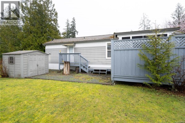 Side view of mobile home with shed and deck, surrounded by grass - 256 3042 River Rd, Chemainus