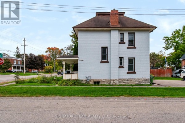 Side exterior of a white brick house with stone foundation and green lawn. - 256 Maple Avenue, Pembroke