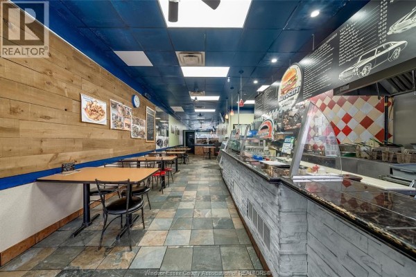 Interior of Autocity restaurant showing dining tables, service counter, and menu boards. - 256 Ouellette Avenue, Windsor