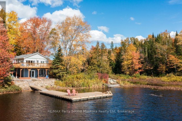 View of the lakefront house with a dock and colorful fall foliage. - 256 Tahinca Road, Whitestone