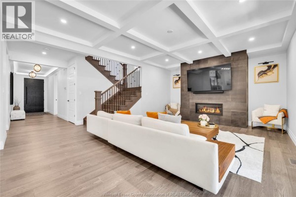 Contemporary living room with a white sectional sofa, fireplace, built-in television, and coffered ceiling. - 256 Xavier Circle, Lakeshore