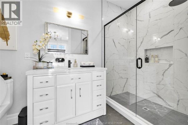 Modern bathroom vanity with white cabinets and a large glass-enclosed shower with marble tile. - 256 Xavier Circle, Lakeshore