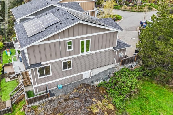 Side view of a brown house with multiple windows and landscaping. - 2562 Rosevista Pl, Langford
