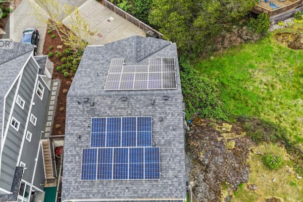 Top view of house roofs with multiple solar panels and surrounding green slopes. - 2562 Rosevista Pl, Langford
