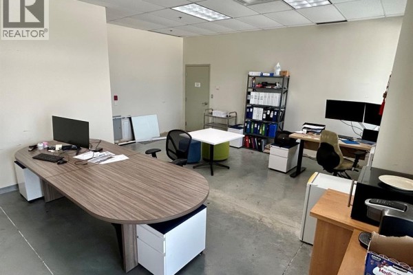 Spacious office with multiple workstations, desks, chairs, filing cabinets, and large windows offering city views. - 2565 Ouellette Avenue Unit# 300, Windsor