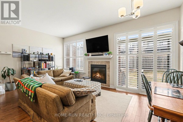 Living room with fireplace, television, shutters, and hardwood floors. - 257 Dolce Crescent, Ottawa