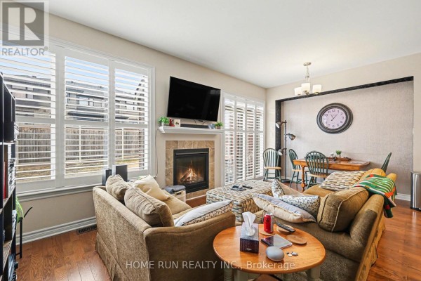 Living and dining area with fireplace, large windows, and wood furniture. - 257 Dolce Crescent, Ottawa