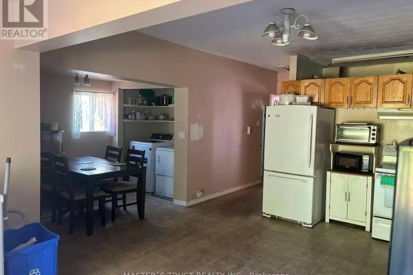 Open concept kitchen and dining area with wood cabinets, white appliances, and a laundry machine. - 257 Leslie Street, Greater Sudbury